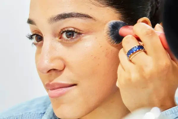 A woman tests a Real Techniques Expert Face Makeup Brush on her face