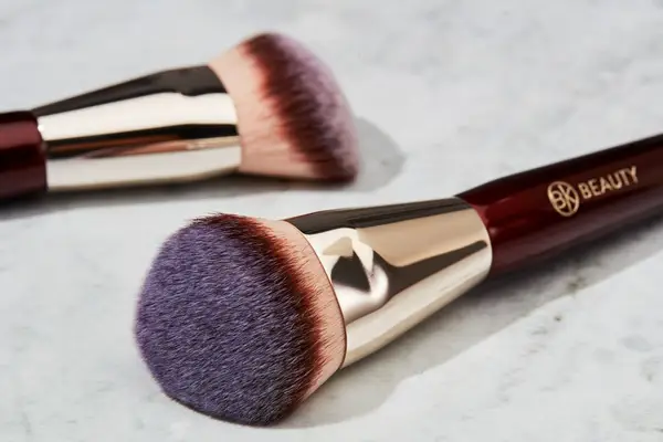 A collage of testers using foundation brushes to apply makeup on their face