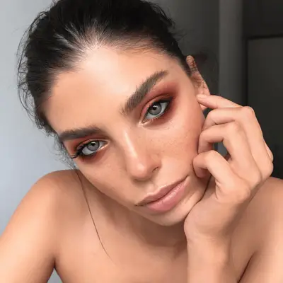 Lucy Hale wears shimmering copper and gold eyeshadow with red lipstick and a red lace dress