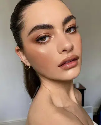 model wears copper shadow with bold brows and brown eyeliner