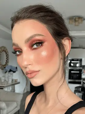 model wears a smoky eyeshadow copper look that has black shadow in the crease and copper in the center of the lid, paired with a soft, neutral glossy lip