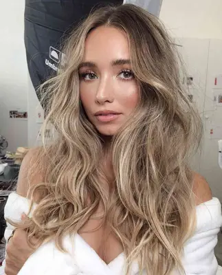 model wears natural makeup look consisting of light pink lips, cheeks, and mascara with soft neutral shadows on the eyes