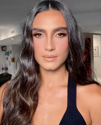 Model is wearing soft peach and pink makeup with defining liquid eyeliner 