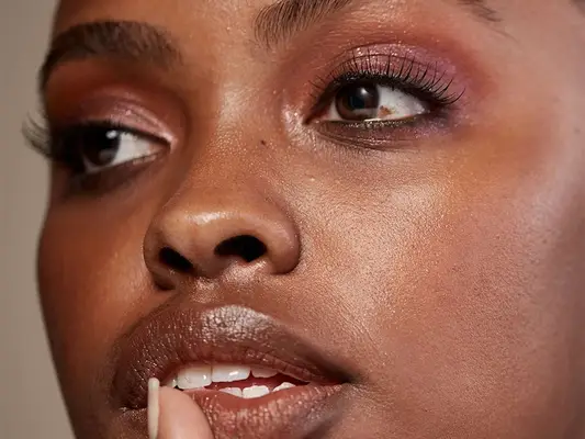 Close-up of woman wearing false lashes, shimmery pink eyeshadow, and shimmery lipstick