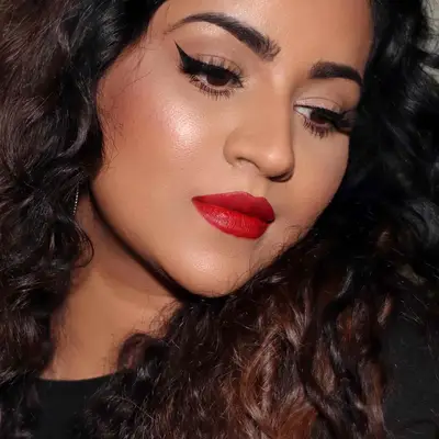 Makeup artist wears classic black bat wing eyeliner and red lipstick