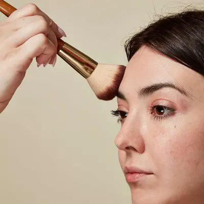 Woman adds powder to her forehead
