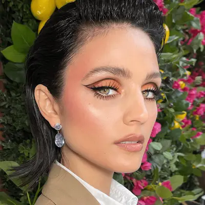 Model with short slicked back hair and bright orange eyeshadow