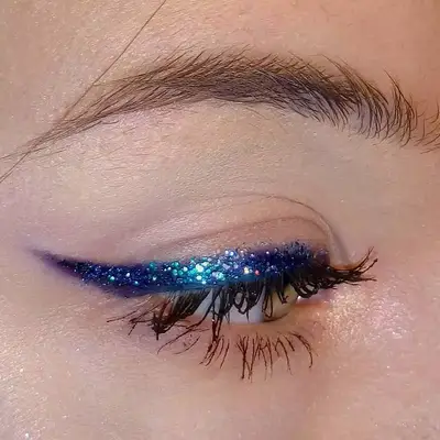 Close-up of eye with indigo glitter winged liner