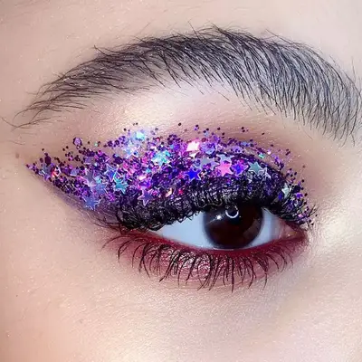 Close-up of eye with iridescent purple star confetti glitter