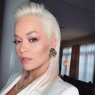 Rita Ora wears pink glitter eyeshadow, glossy lips, and platinum hair