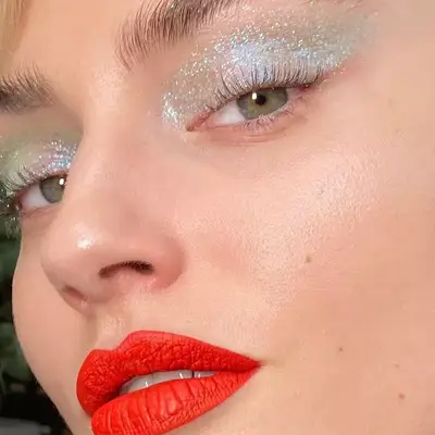 Close-up of model with mint glitter eyeshadow and red lipstick
