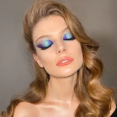 Model with purple and teal mermaid-inspired bedazzled glitter eye makeup look