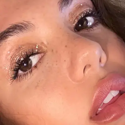 Close-up of model with scattered silver glitter eye makeup and glowing skin