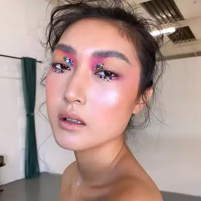 Model with pink and neutral makeup and multicolored eye gems