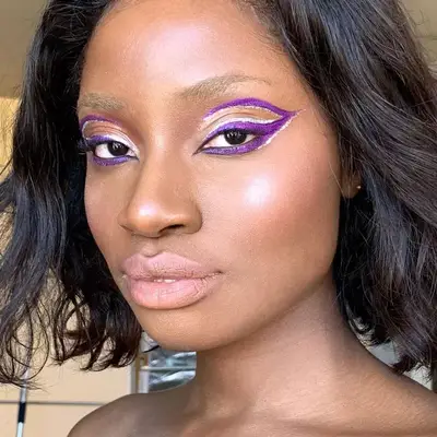 Model with purple and silver graphic eyeliner and radiant skin