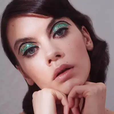Model wears glitter eyeshadow and black graphic liner