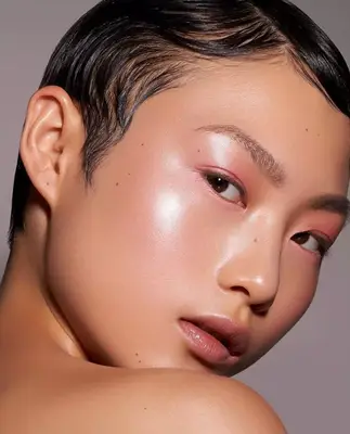 model is wearing a soft pink eyeshadow look with prominent highlighted skin