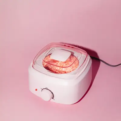 Close up of a wax warmer with pink beads on a pink backdrop