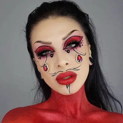 Makeup artist with red body paint, eyeshadow, and lipstick, black facial hair lines, and face gems