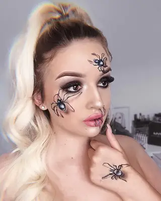 Woman with glam eye makeup, pink lipstick, and spider makeup design