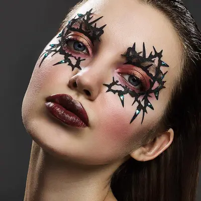Model with copper eyeshadow, burgundy lipstick, and thorn decals around eyes