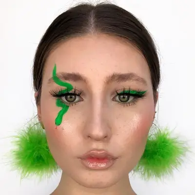 Woman with radiant skin, blush, and green snake eye makeup
