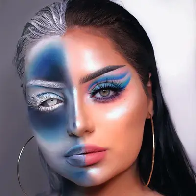 Makeup artist wears half-full glam look with blue eyeshadow, half-X ray blue face paint