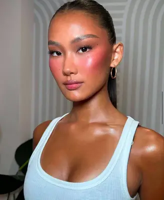 model wears makeup look with visible pink blush
