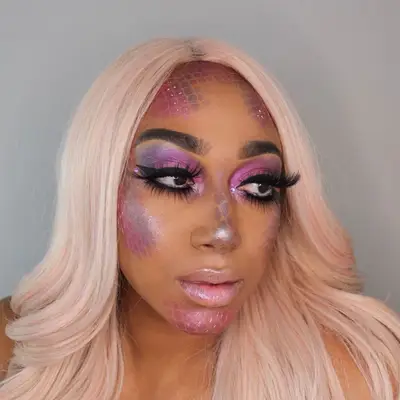 Makeup artist wears pink wig and mermaid-inspired makeup look with scales