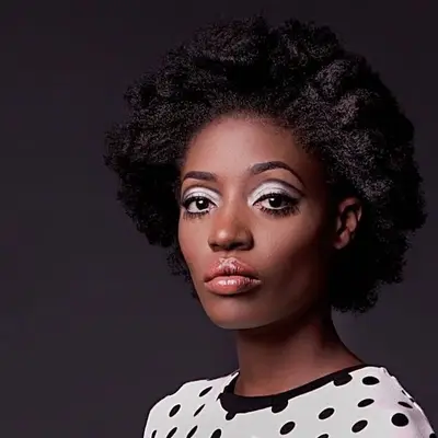 Model wears simple makeup look with Twiggy-inspired lower lashes, white eyeshadow, and glossy lips