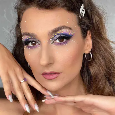 Shimmery purple eye makeup with spiraling silver and gold rhinestones