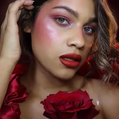 Makeup artist wears red-toned makeup look with radiant skin and statement lipstick