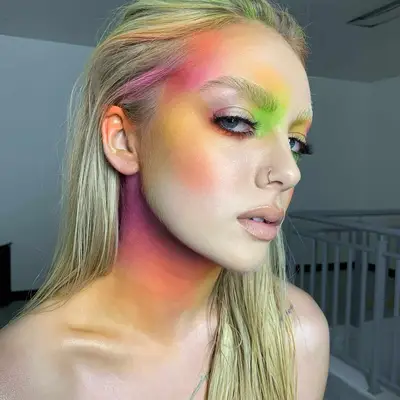 Pigmented makeup look with oranges, greens, and pinks on face and hair