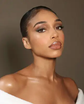 Lori Harvey wears a taupe smoky eyeshadow look and brown tone natural lip color with gloss
