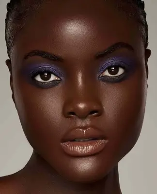 Model wears frosted deep purple eyeshadow on the lids with black shadow applied underneath the bottom line
