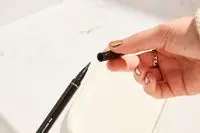 Hands hold and open e.l.f. Cosmetics Intense H2O Proof Eyeliner Pen