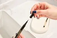 Hands hold a COVERGIRL Exhibitionist Lash Enhancing Liquid Eyeliner