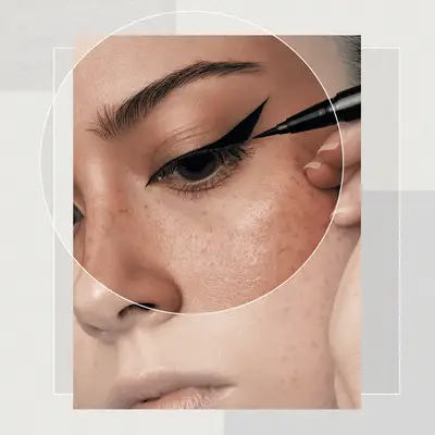 Close Up of Woman Applying Black Liquid Eyeliner in a Cat-Eye Style on a Designed Background