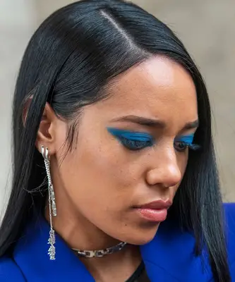 A young woman wears turquoise eyeshadow