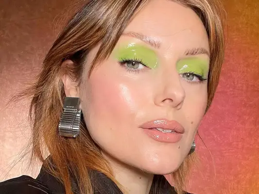 Close up of makeup artist Katie Jane Hughes with a glossy bright green eyeshadow look.