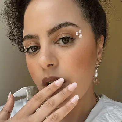 Close up of a MYM Beauty editor wearing three white floral decals made with eyeliner.