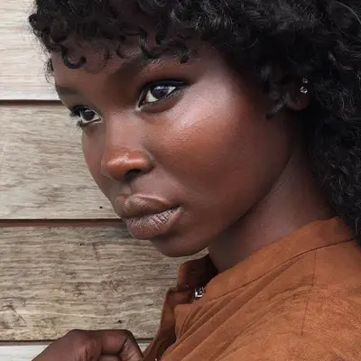 Model wears minimal, neutral makeup look with radiant skin