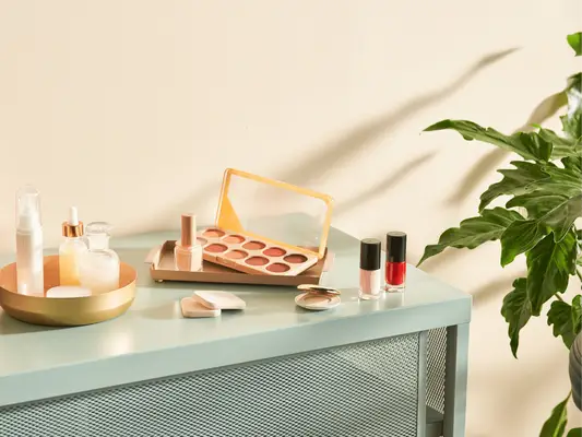 A counter with makeup on it and a plant in the corner
