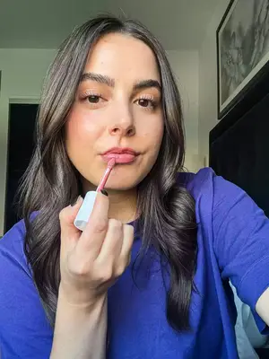 A collage of three testers applying different colored lip glosses to their lips 
