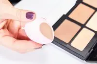 A person applies the KVD Beauty Shade + Light Powder Face Contour Palette