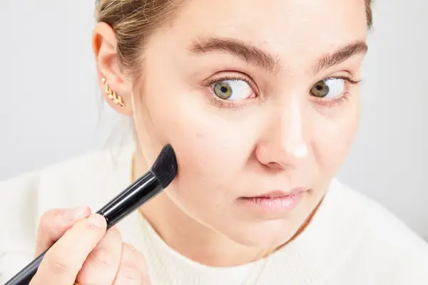 A person applies Charlotte Tilbury Filmstar Bronze & Glow Contour Duo powder to their face