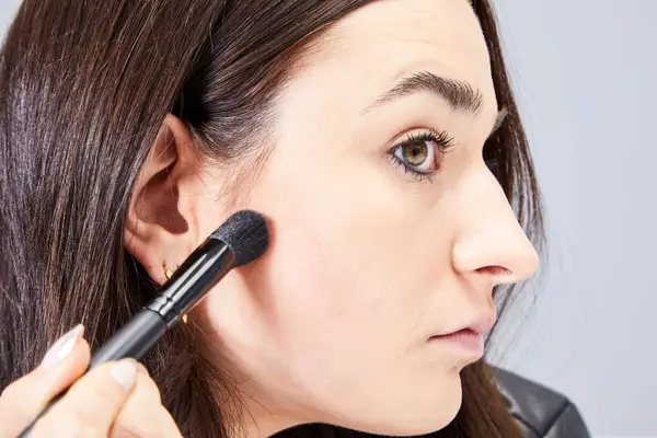 A person applies the Hourglass Ambient Lighting Palette