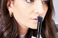 A person applies the Hourglass Ambient Lighting Palette