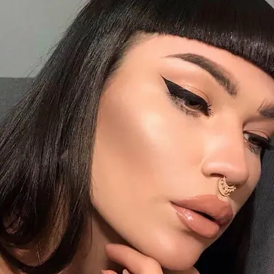 Woman with nude makeup, tinted glossy lips, and black winged liner