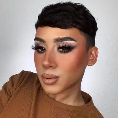 Creator wears blushed cheeks, nude glossy lips, and full glam smoky eye